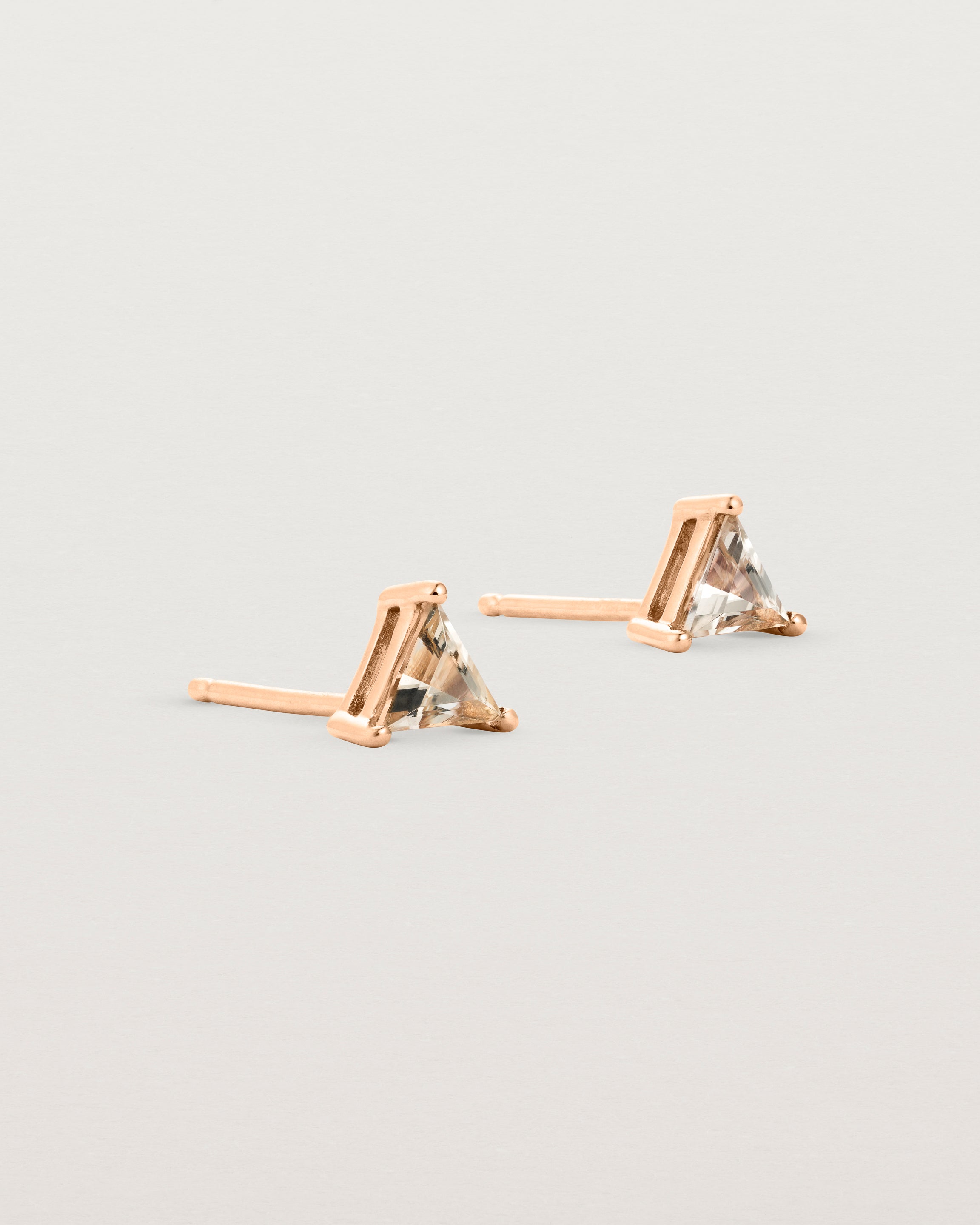 A pair of rose gold studs featuring a triangle shaped light yellow rutilated quartz