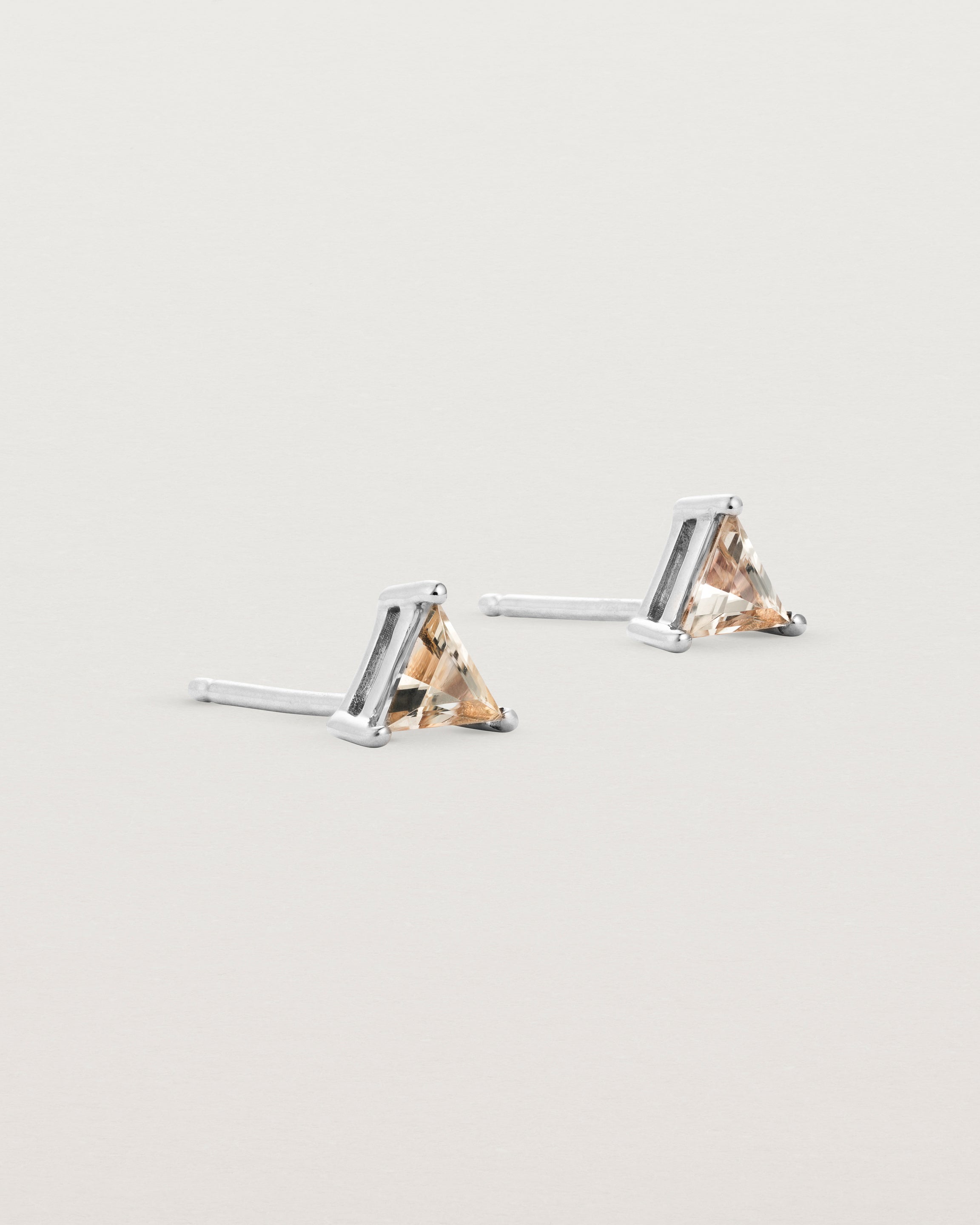 A pair of sterling silver studs featuring a triangle shaped rutilated quartz