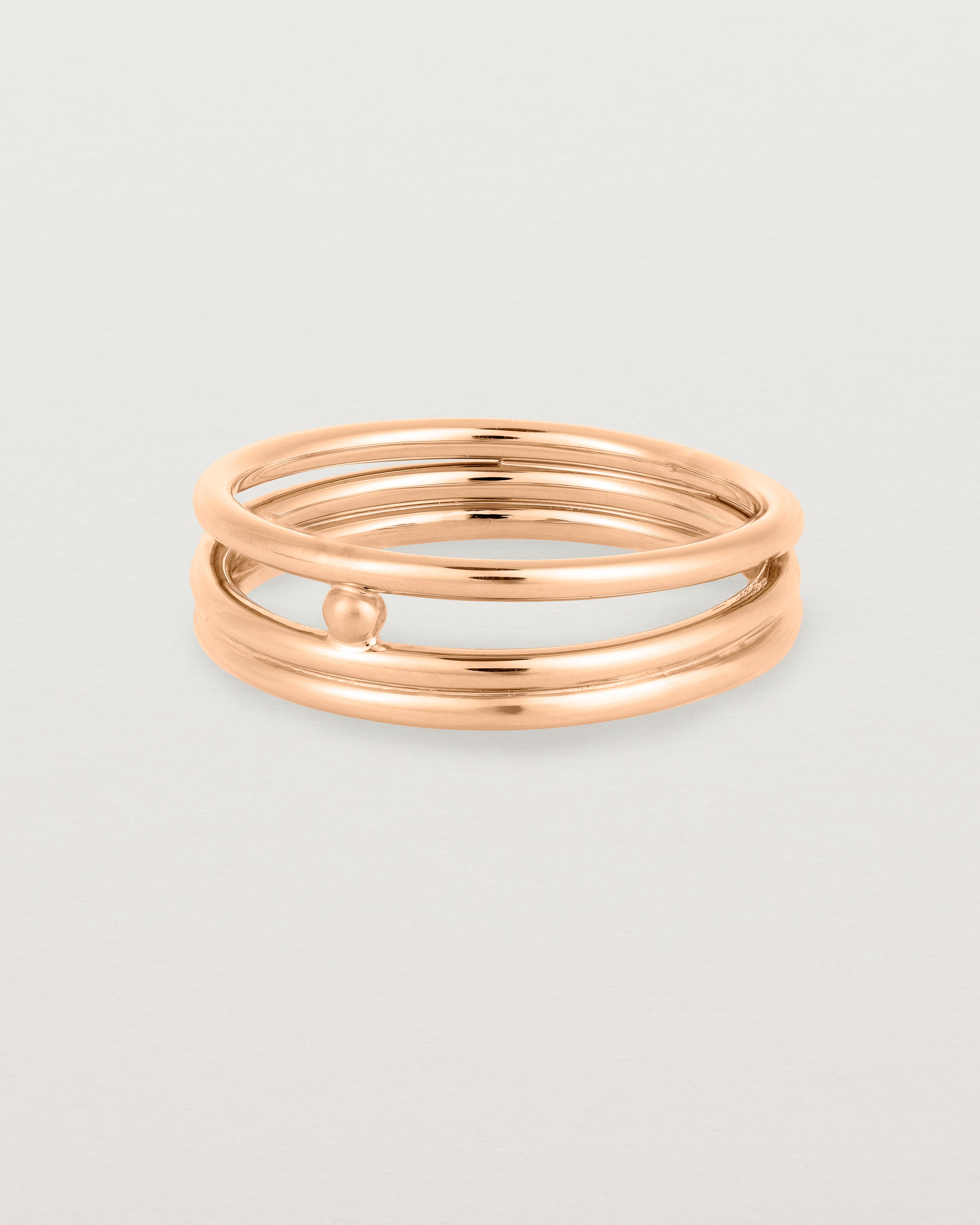 layered rose gold ring featuring a yellow gold ball suspended between two bands