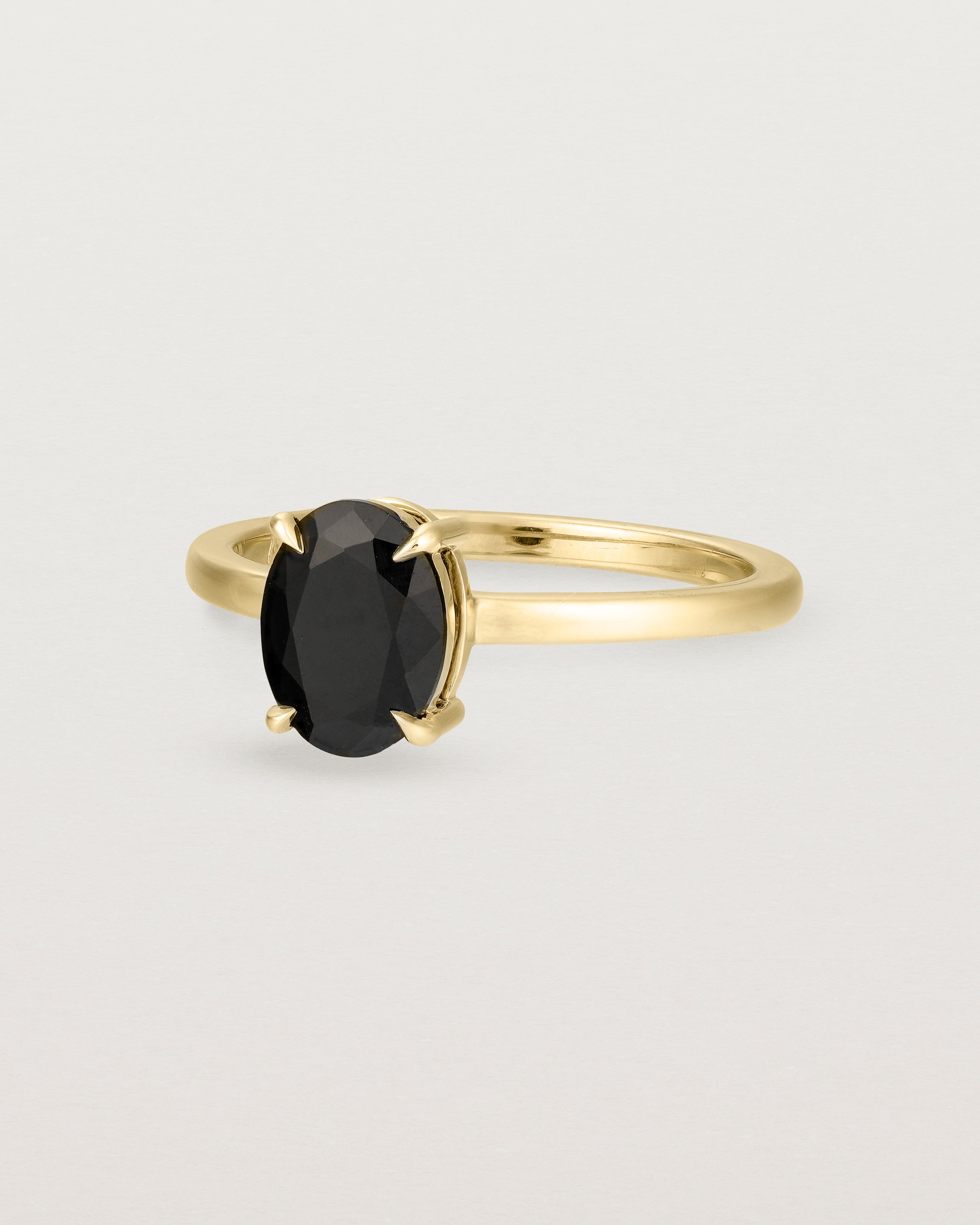 Angled view of the Una Oval Solitaire | Black Spinel | Yellow Gold.
