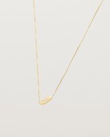 A yellow gold marquise disc hung on a necklace featuring a small star set white diamond