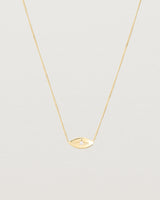 A yellow gold marquise disc hung on a necklace featuring a small star set white diamond