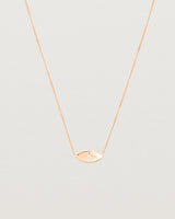 A rose gold marquise disc hung on a necklace featuring a small star set white diamond