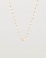 A rose gold marquise disc hung on a necklace featuring a small star set white diamond