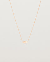 A rose gold marquise disc hung on a necklace featuring a small star set white diamond