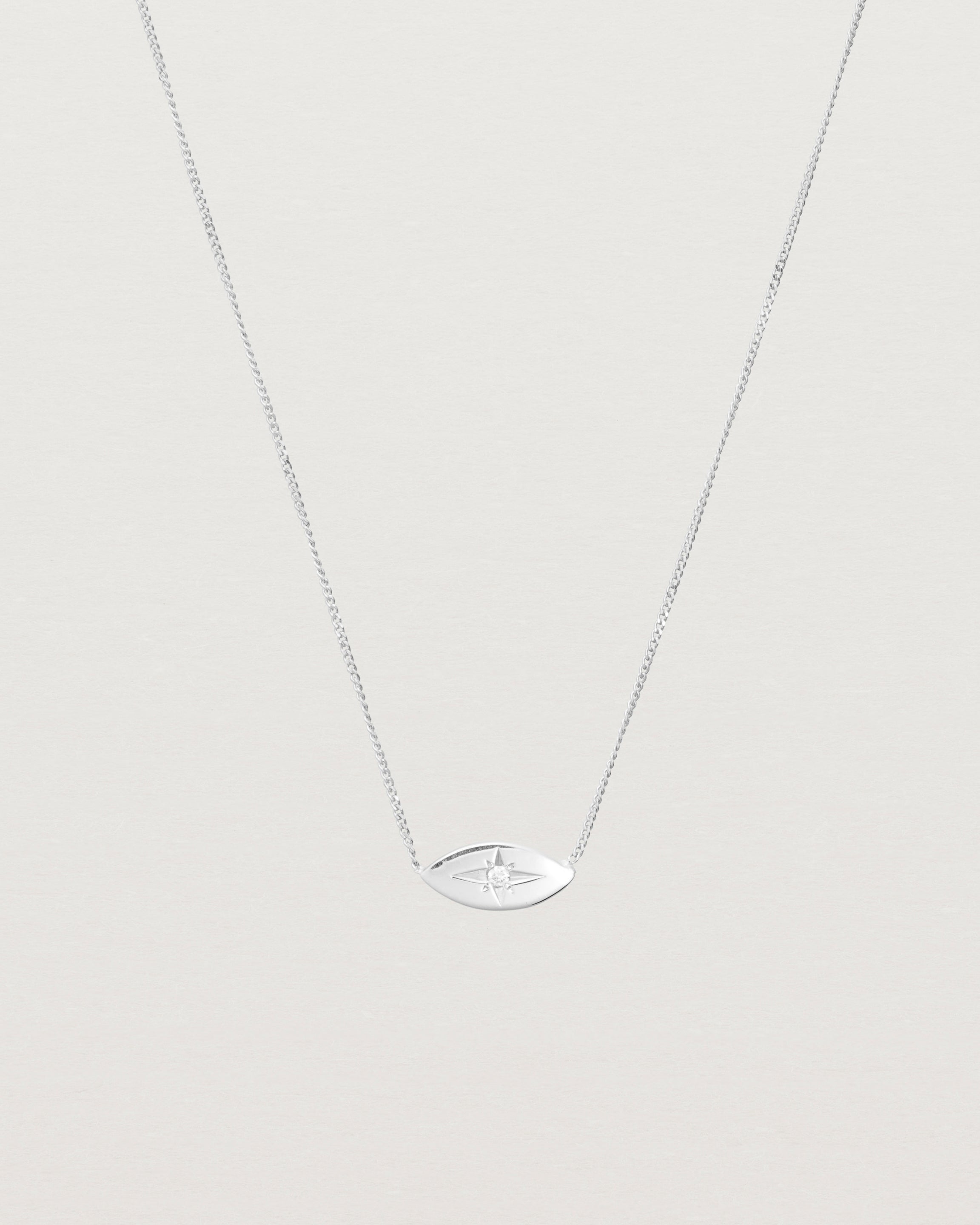 A white gold marquise disc hung on a necklace featuring a small star set white diamond