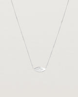 A white gold marquise disc hung on a necklace featuring a small star set white diamond