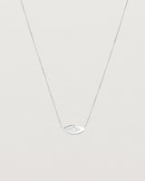 A white gold marquise disc hung on a necklace featuring a small star set white diamond