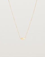 A yellow gold marquise disc hung on a necklace featuring a small star set white diamond