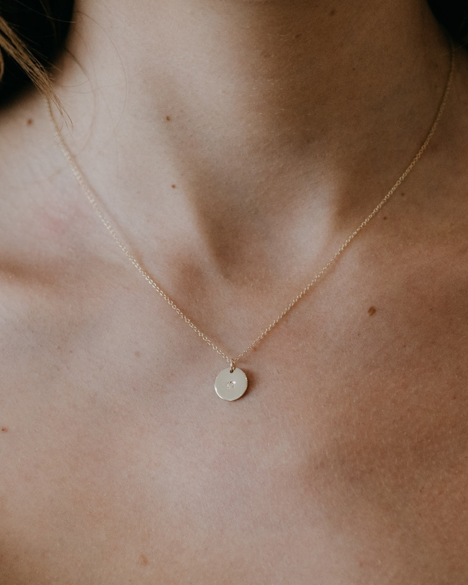 A woman wearing the Mini Initial Necklace in Yellow Gold