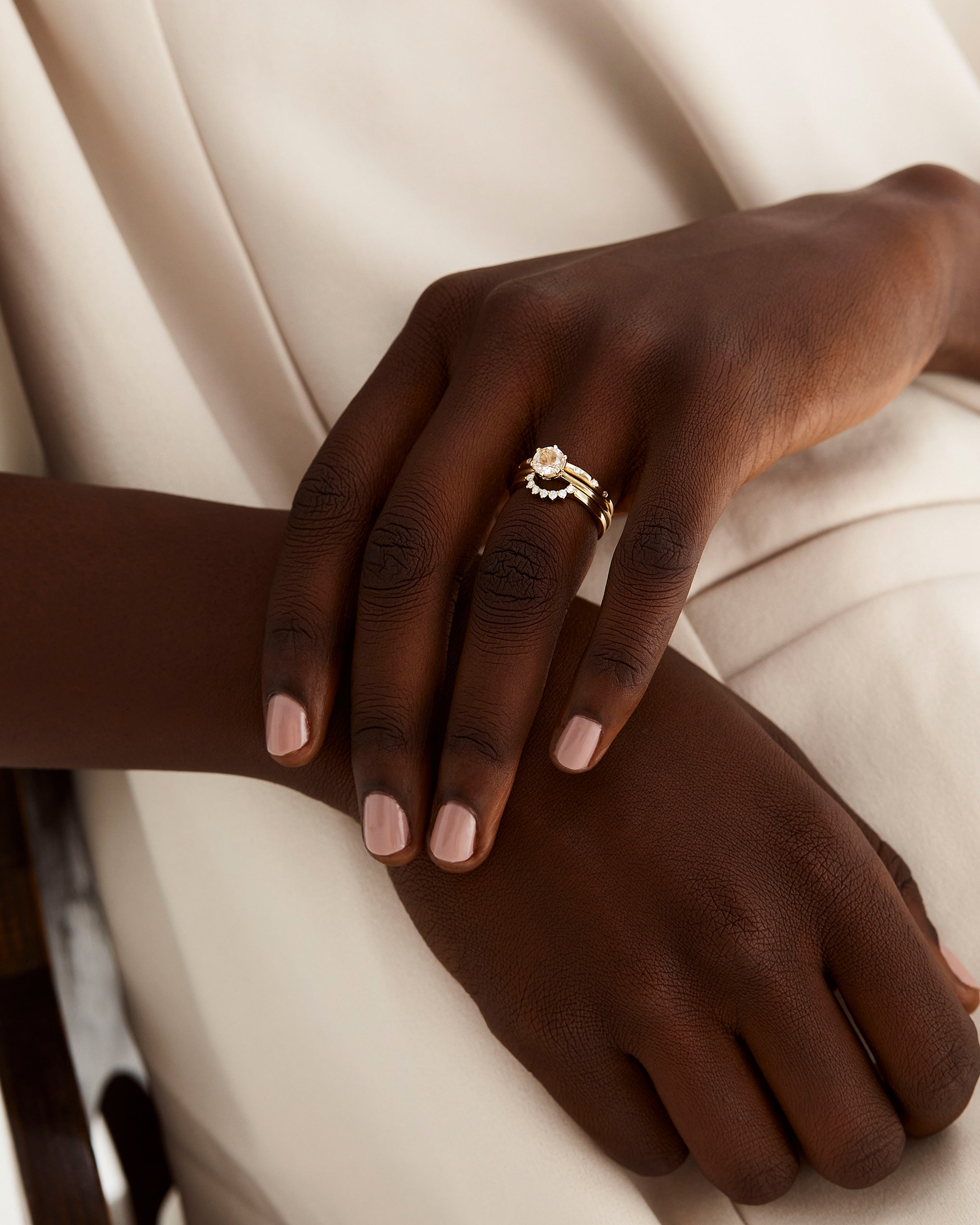 A solitaire style engagement ring featuring a rutilated quartz, worn by a model and stacked with diamond bands and a diamond crown.