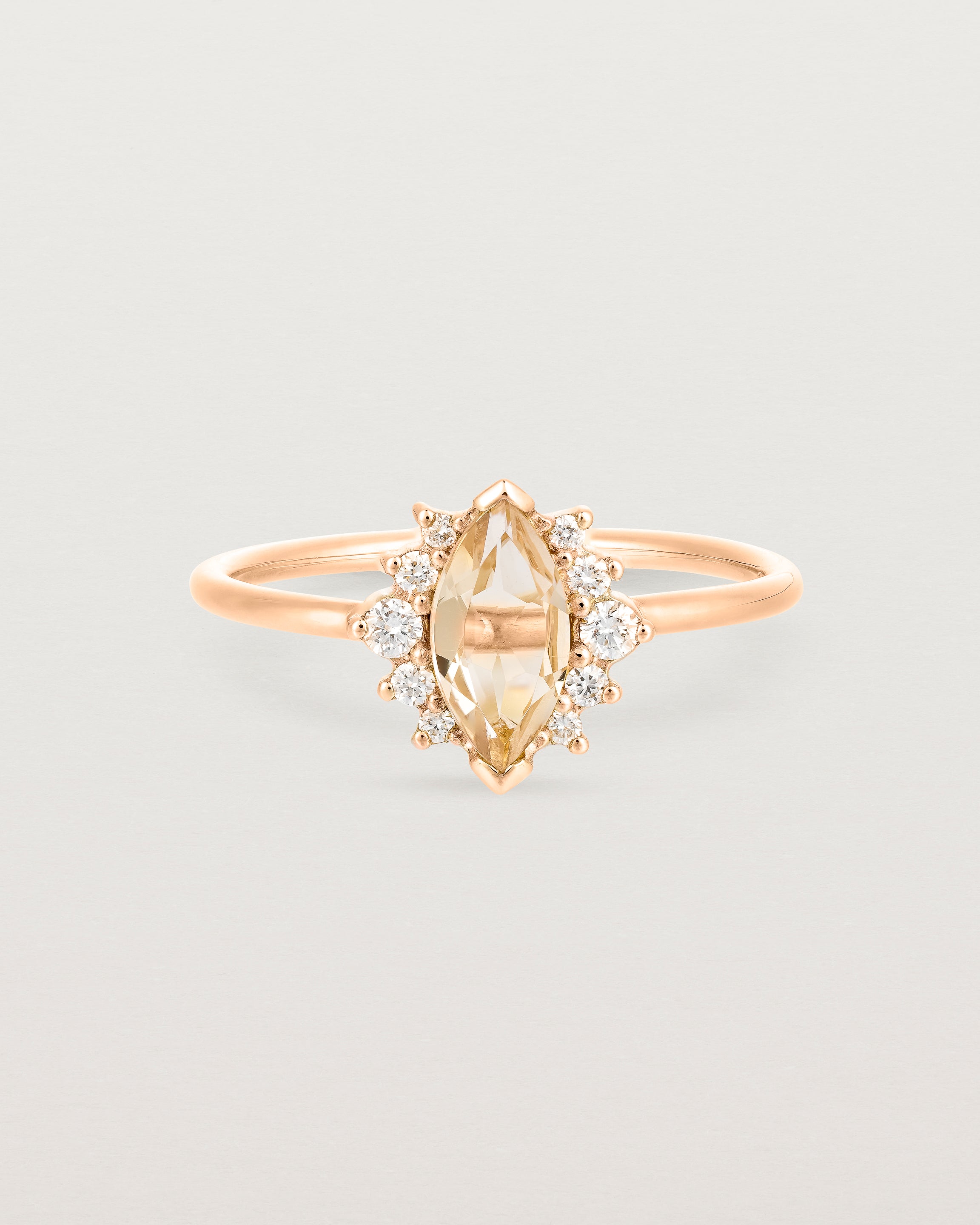 A rose gold ring featuring a marquise champagne quartz with a halo of white diamonds