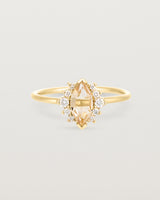 A yellow gold ring featuring a marquise champagne quartz with a halo of white diamonds