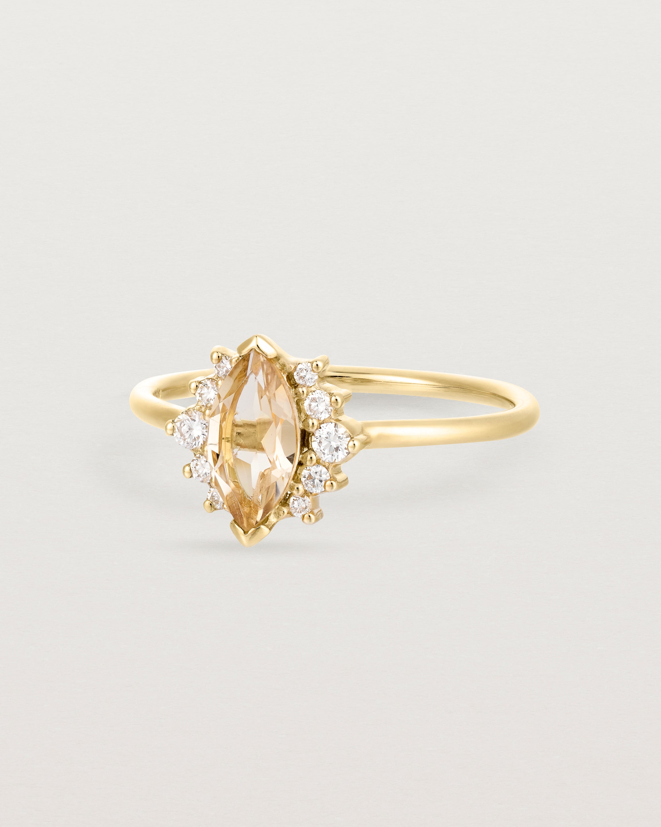 A yellow gold ring featuring a marquise champagne quartz with a halo of white diamonds