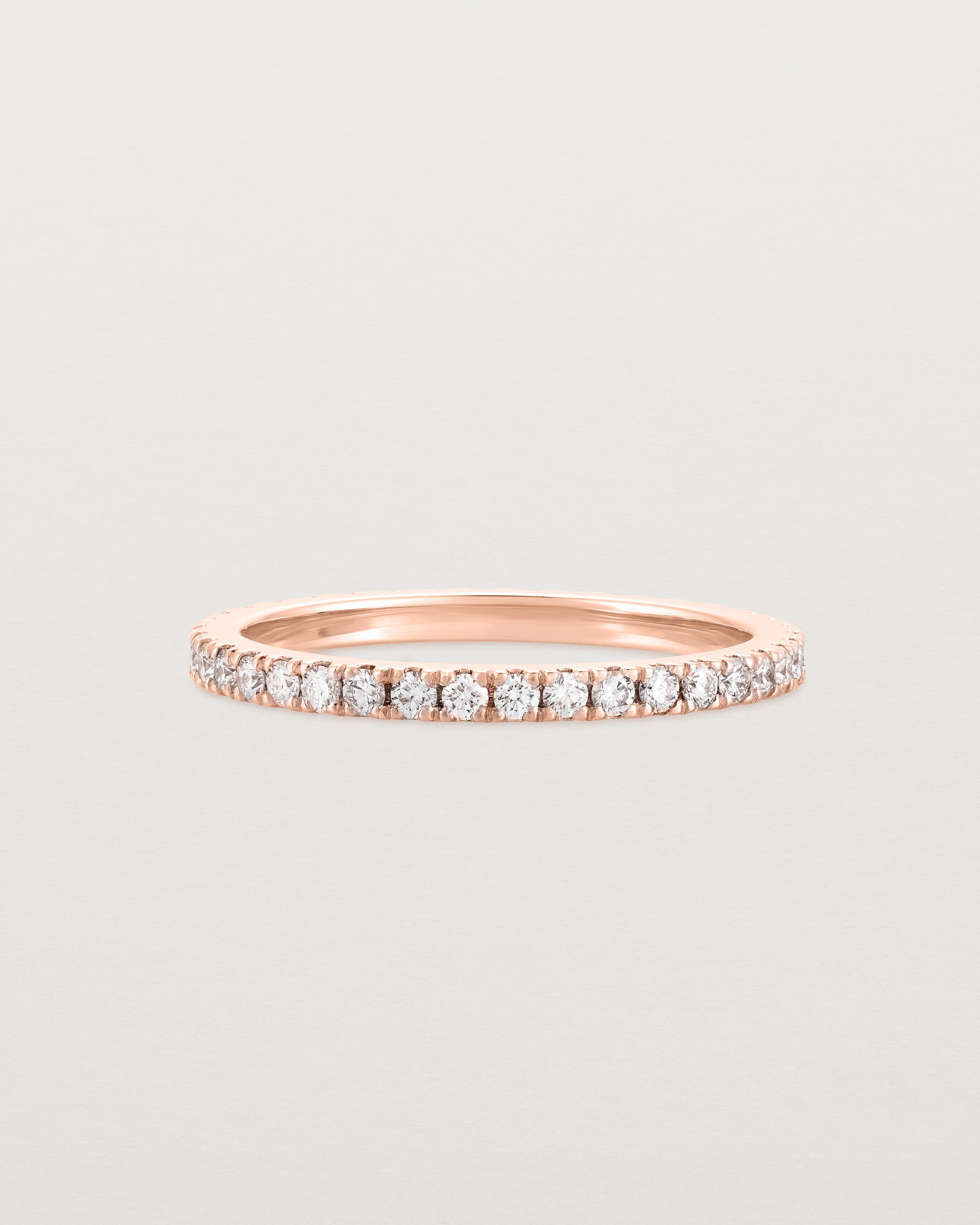 A rose gold band with white diamonds