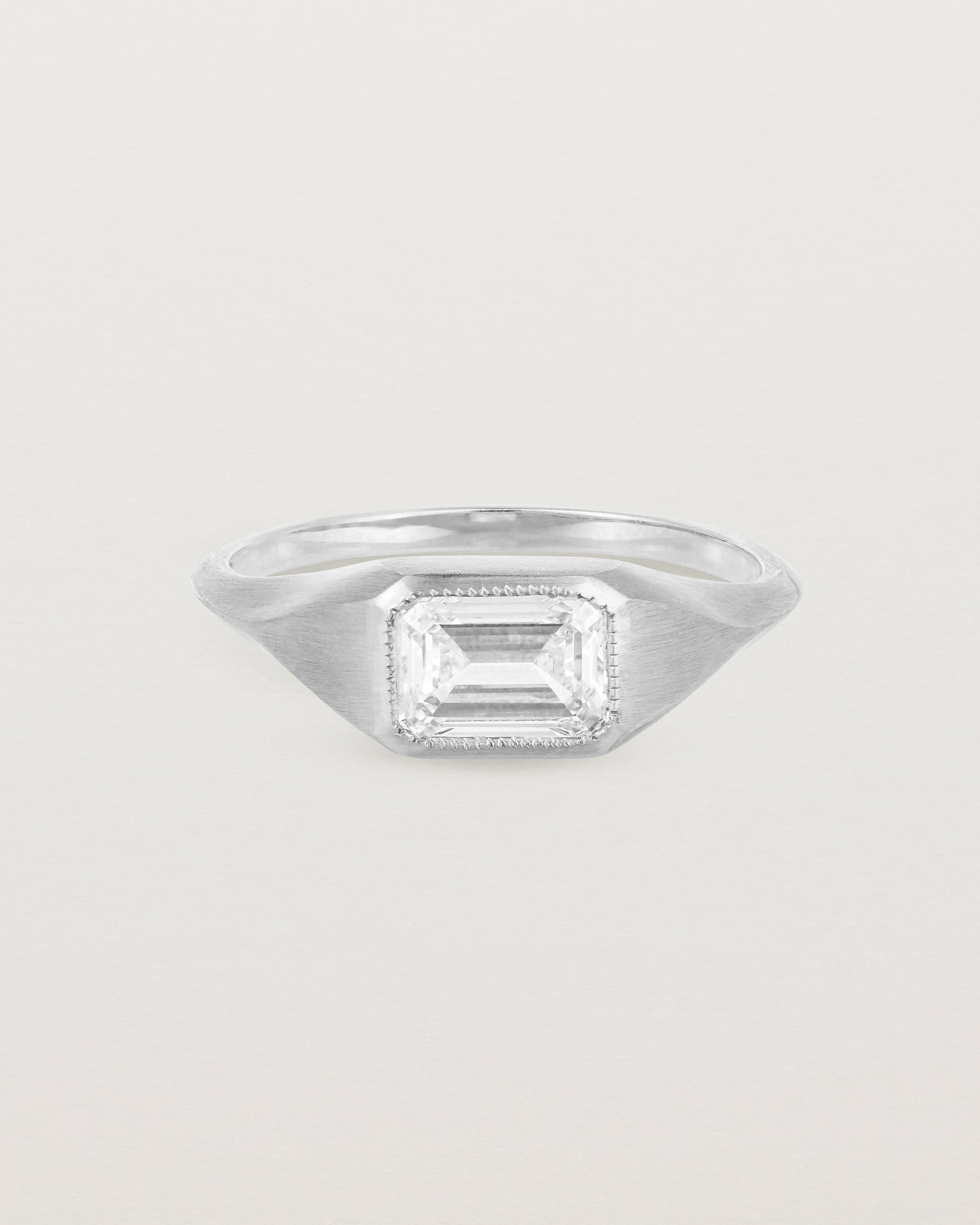 A white gold Signet Ring featuring a emerald cut white diamond