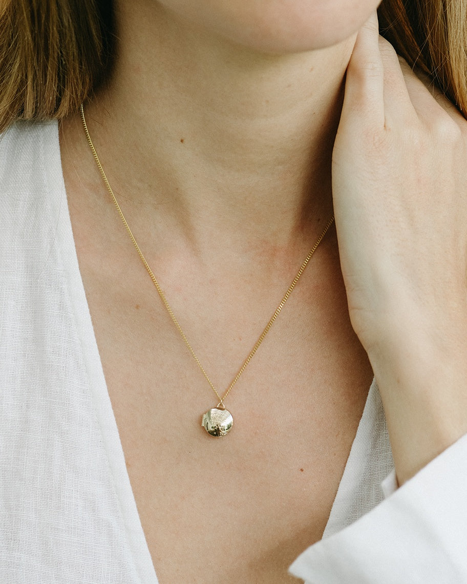 A woman wearing the Clematis Vine Locket in yellow gold.