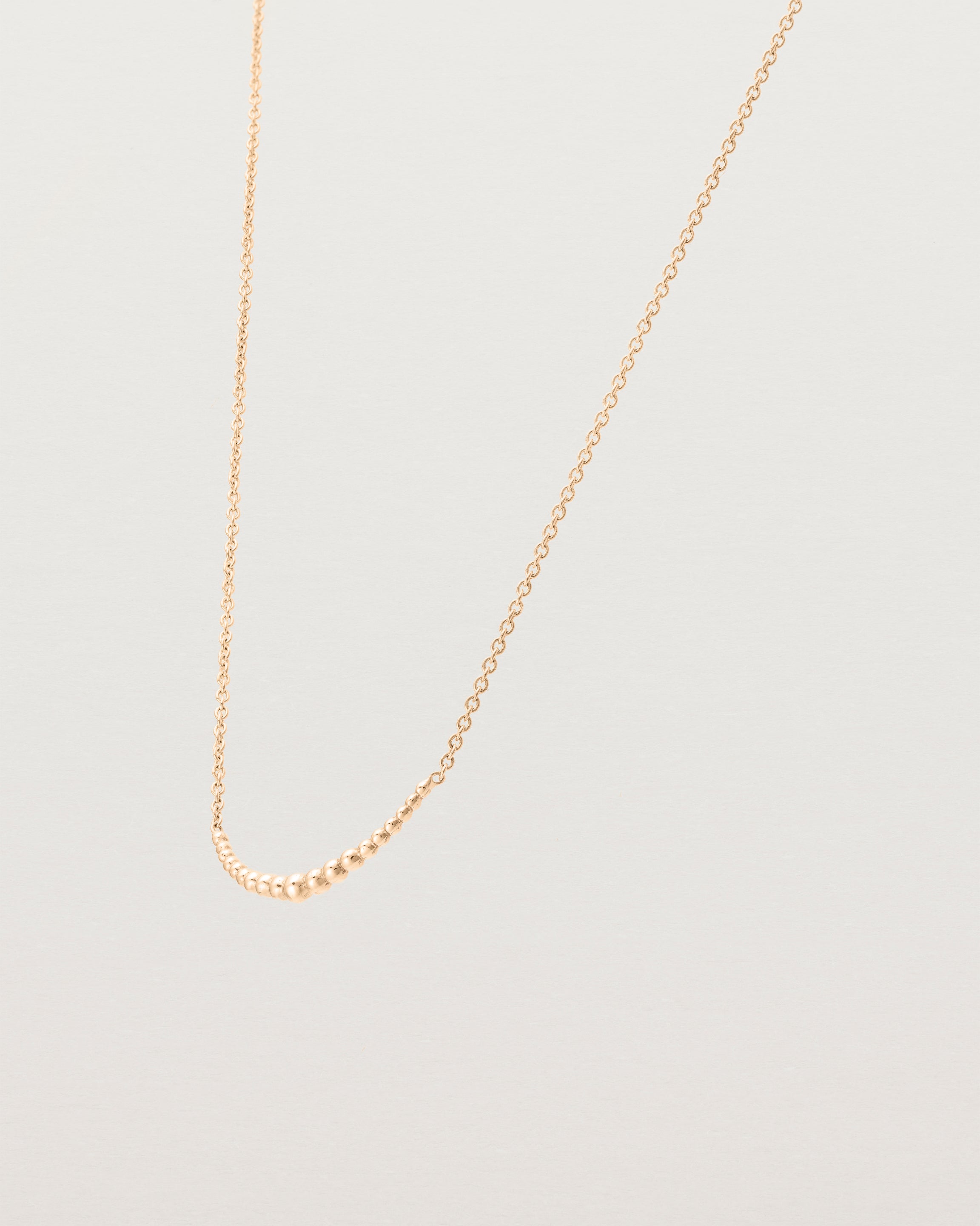 Angled view of the Crescent Necklace in Rose Gold.