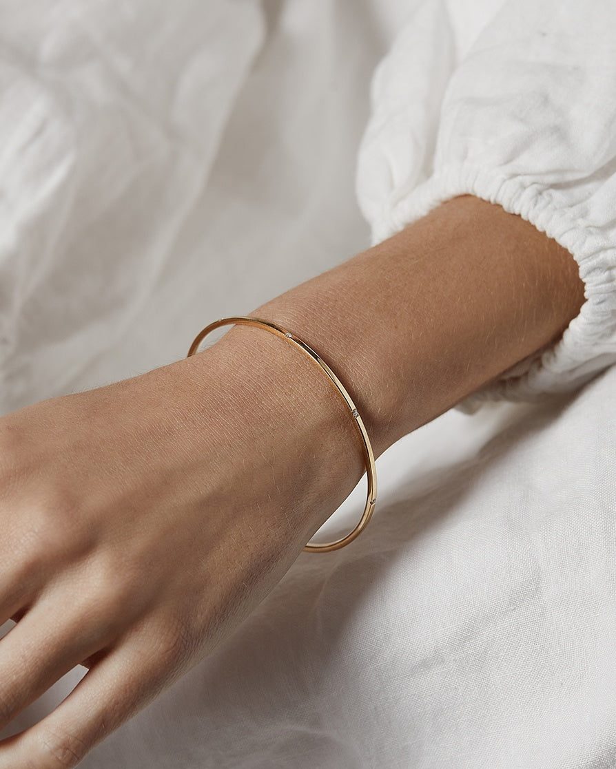 A woman wearing the Diamond Antares Bangle in yellow gold.