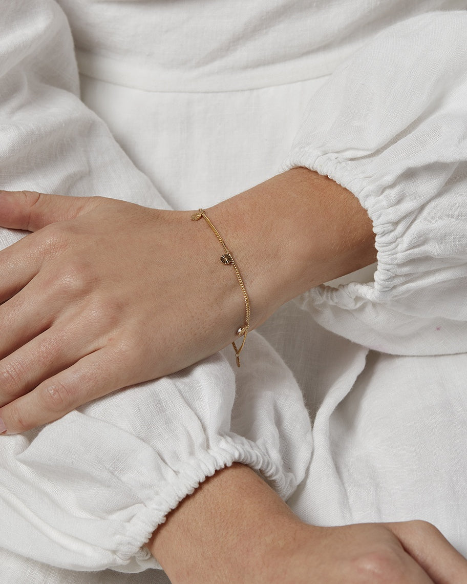 A woman wearing the Jia Charm Bracelet in yellow gold.