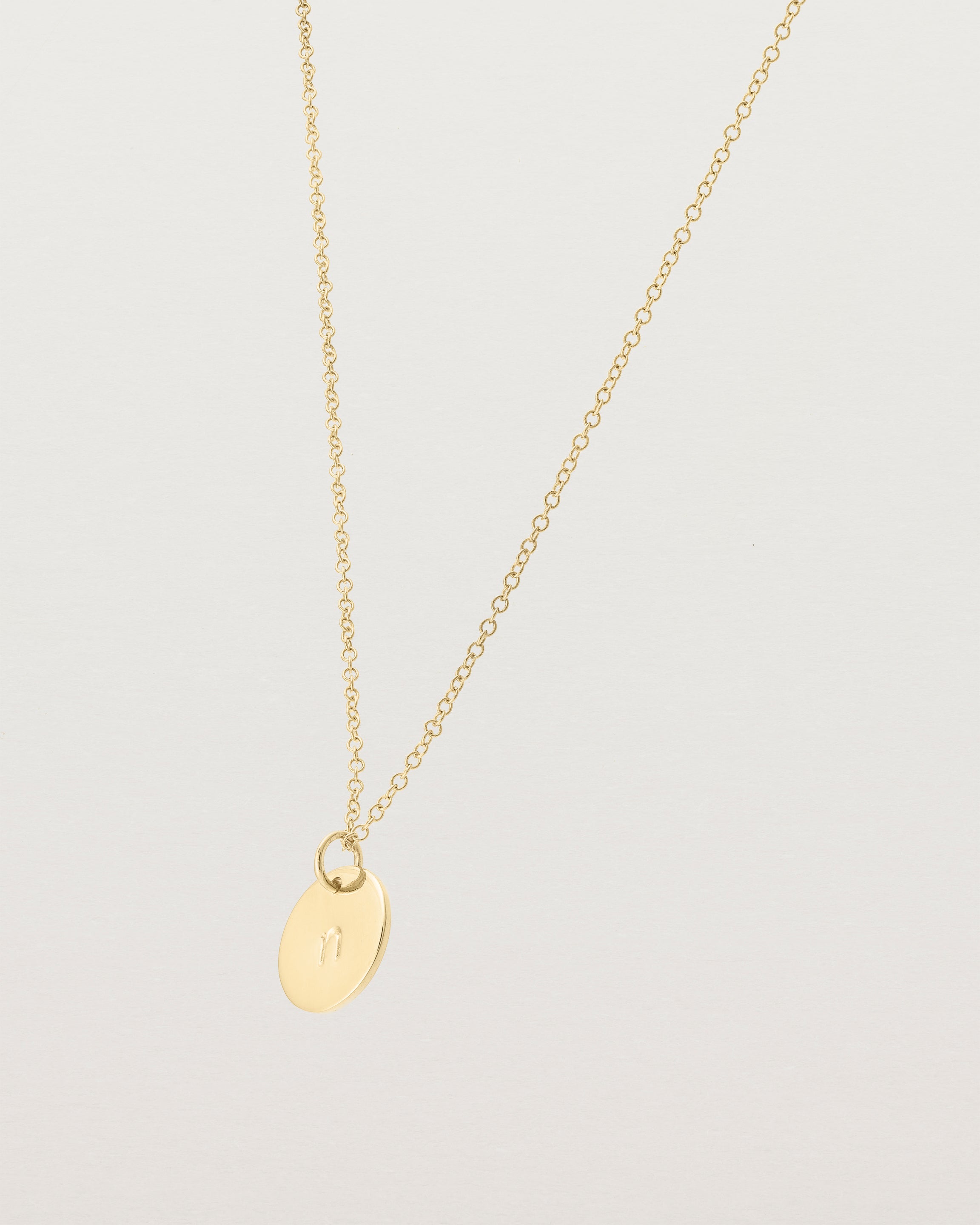 Angled view of the Mini Initial Necklace in Yellow Gold.