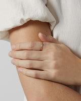 Simple gold ring with tiny dot detail on womans point finger.