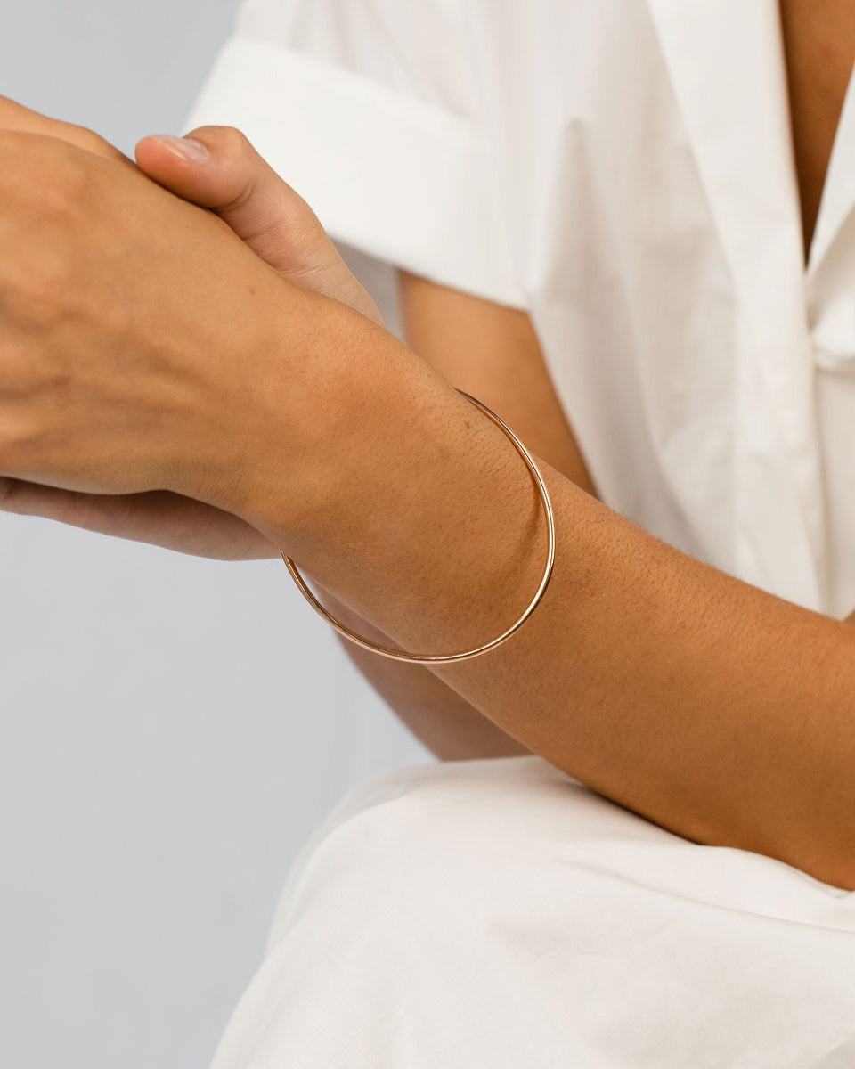 A woman wearing the Oval Bangle in yellow gold.