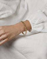 A woman wearing the Pan Bangle in yellow gold.