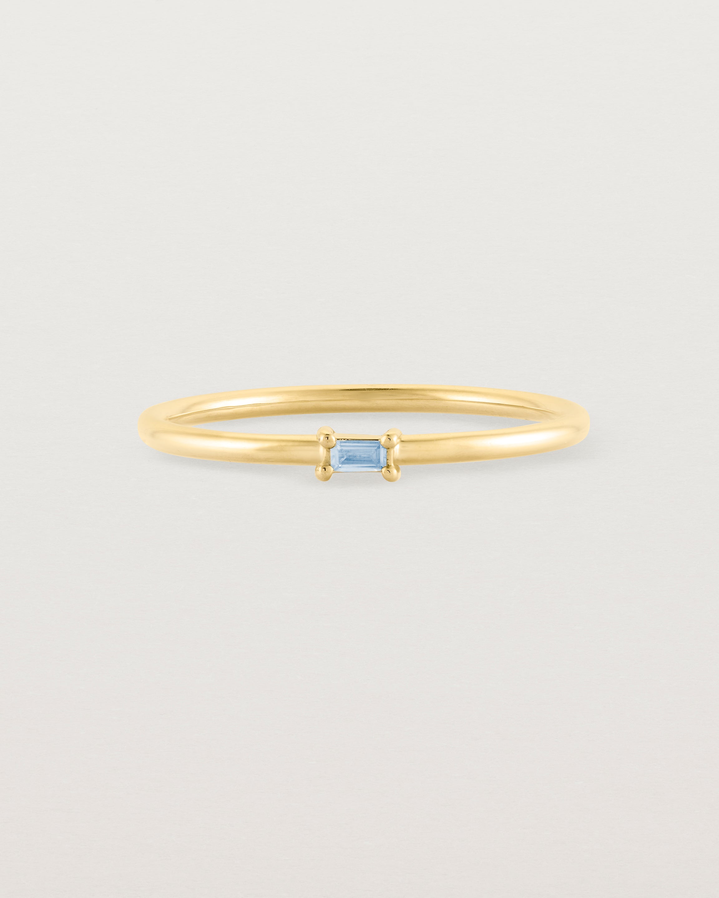fine yellow gold ring featuring a emerald cut pale blue sapphire
