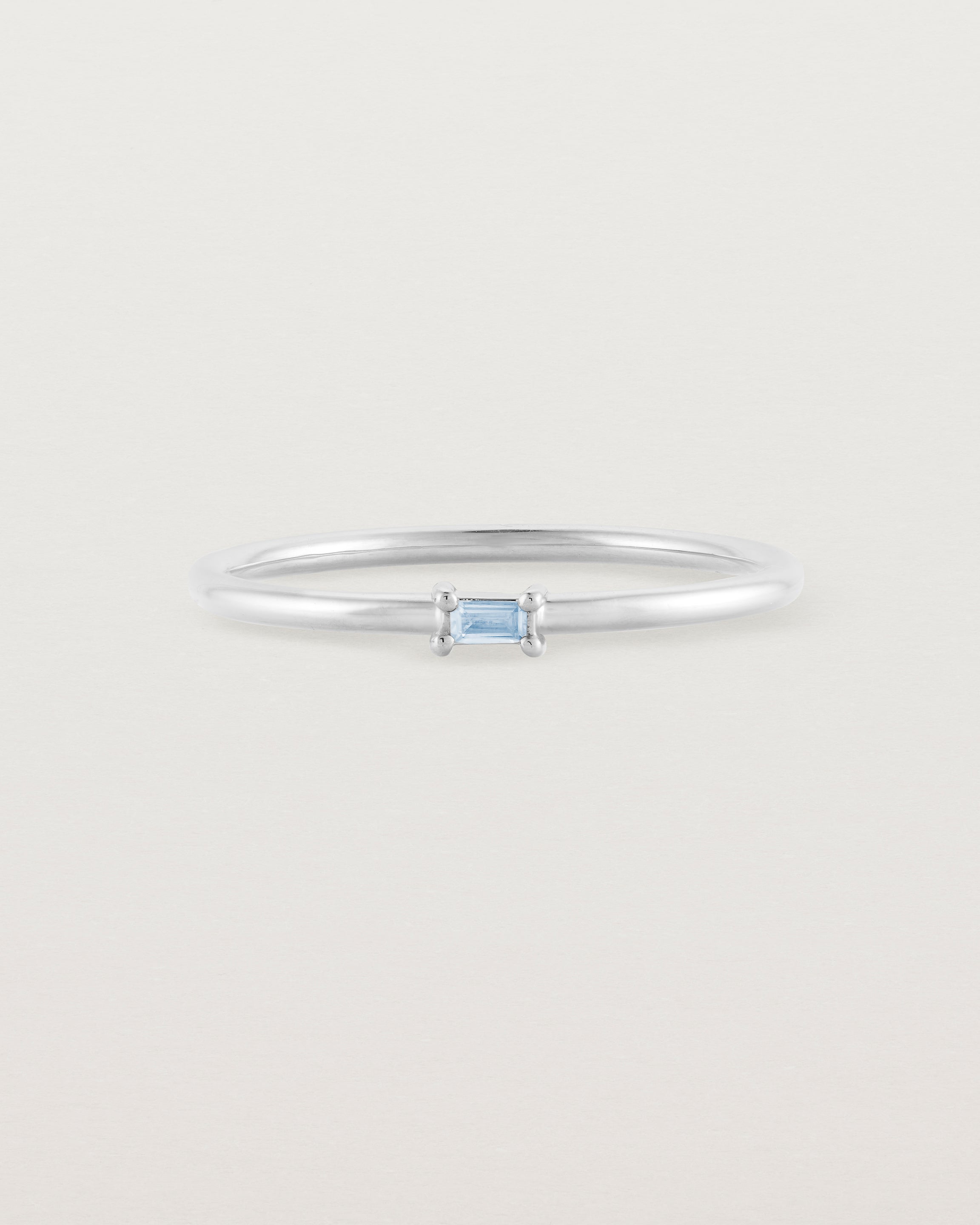 A fine silver ring featuring an emerald cut pale blue sapphire set in the centre of the band