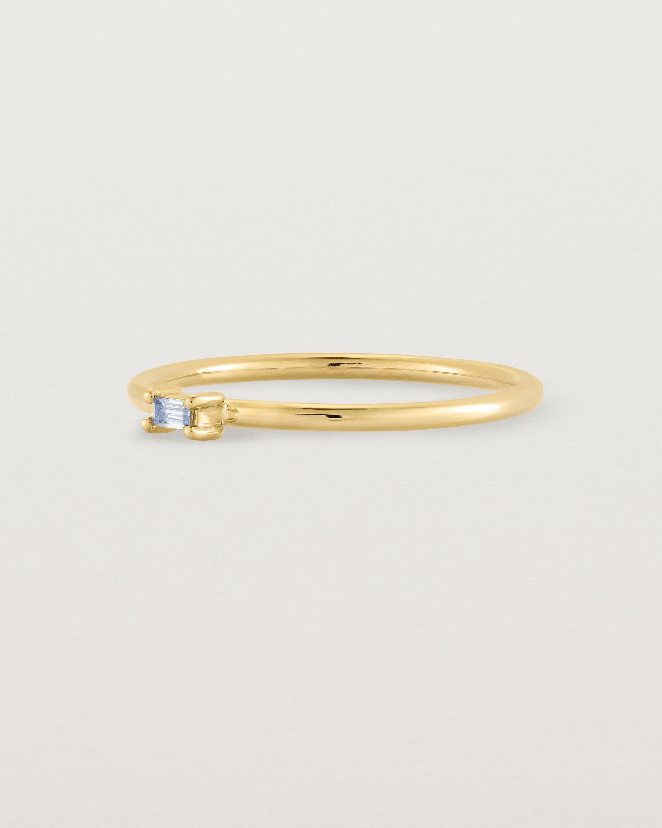 fine yellow gold ring featuring a emerald cut pale blue sapphire