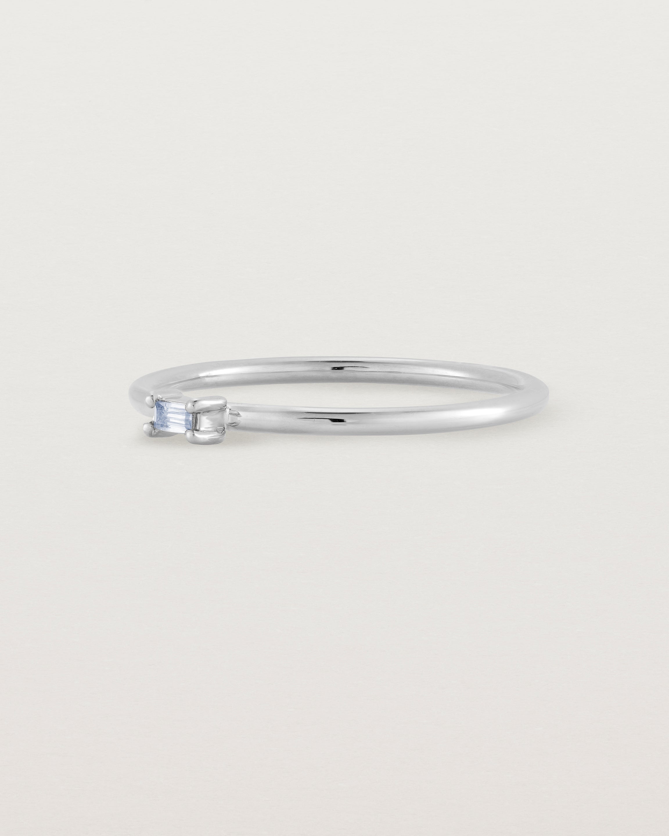 A fine silver ring featuring an emerald cut pale blue sapphire set in the centre of the band
