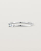 A fine silver ring featuring an emerald cut pale blue sapphire set in the centre of the band