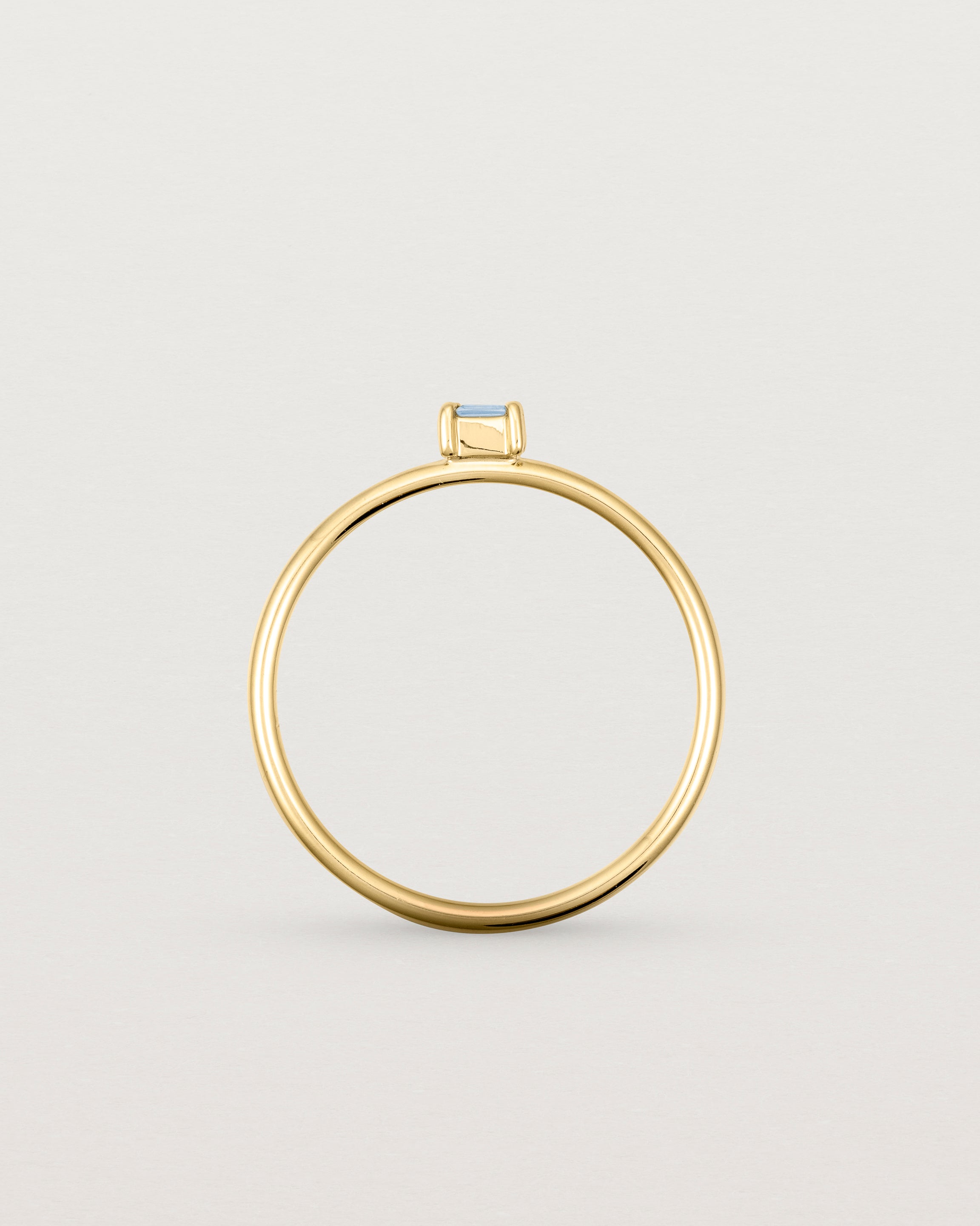 fine yellow gold ring featuring a emerald cut pale blue sapphire