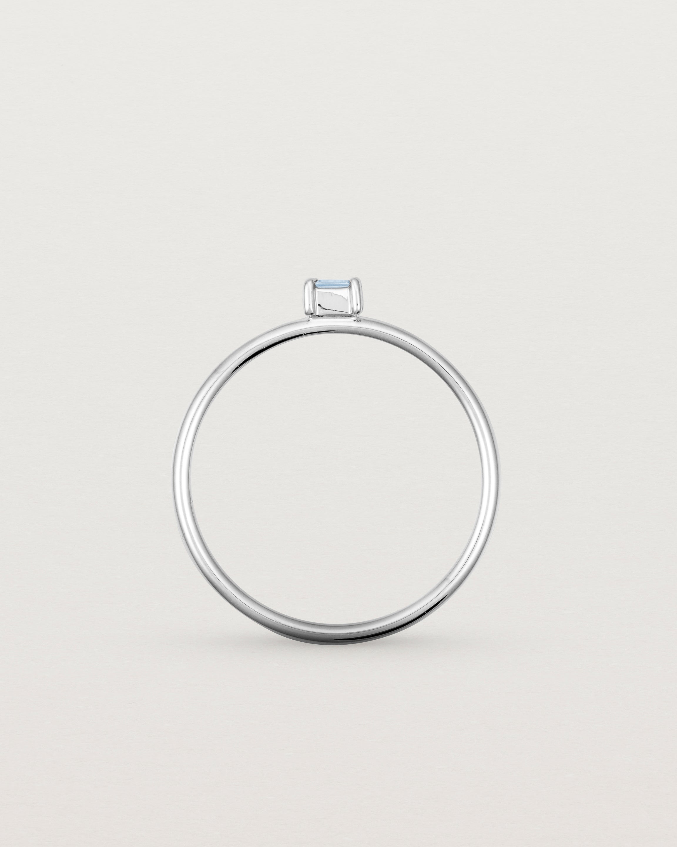 A fine silver ring featuring an emerald cut pale blue sapphire set in the centre of the band