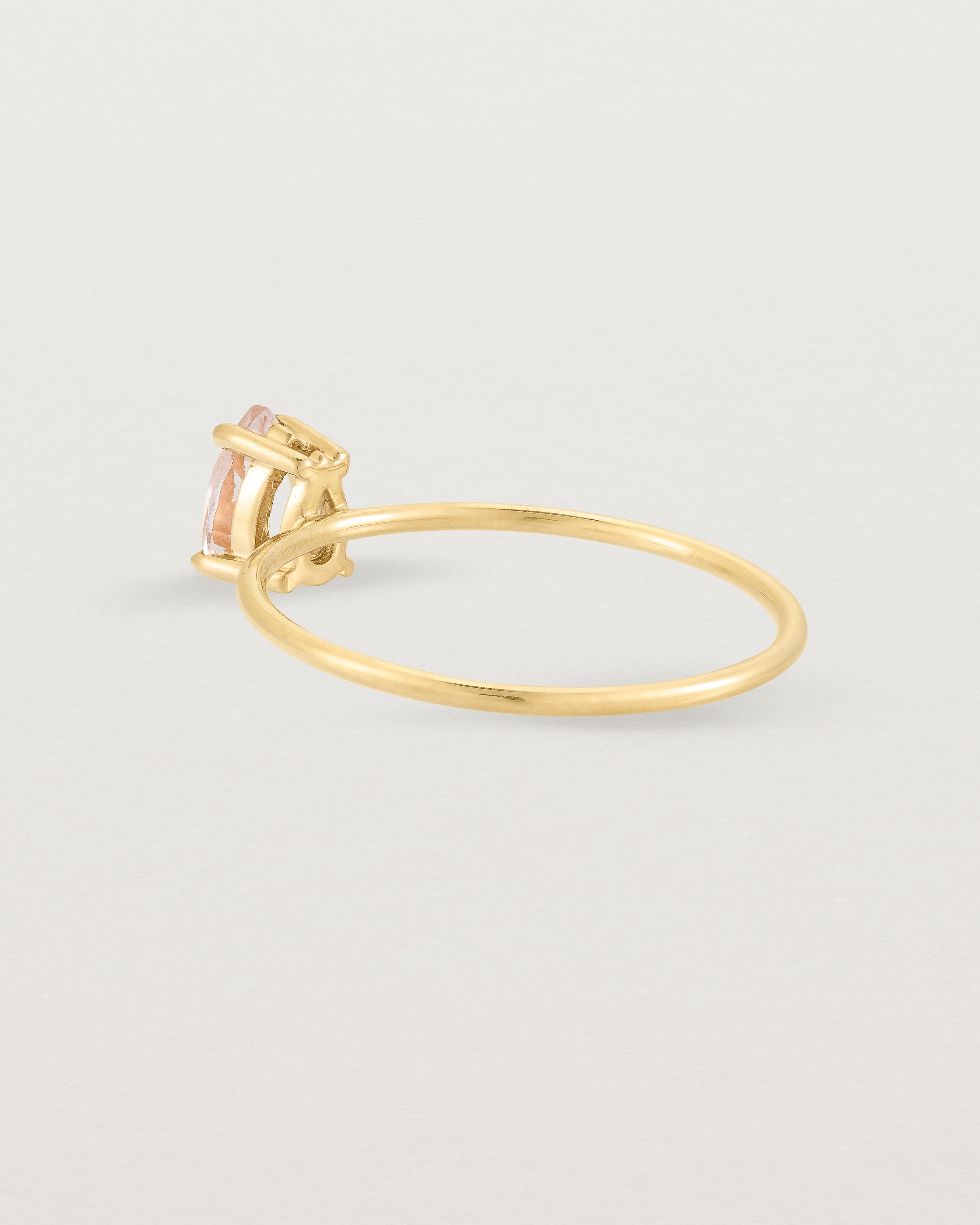 A fine yellow gold ring featuring a pear shaped pink morganite stone