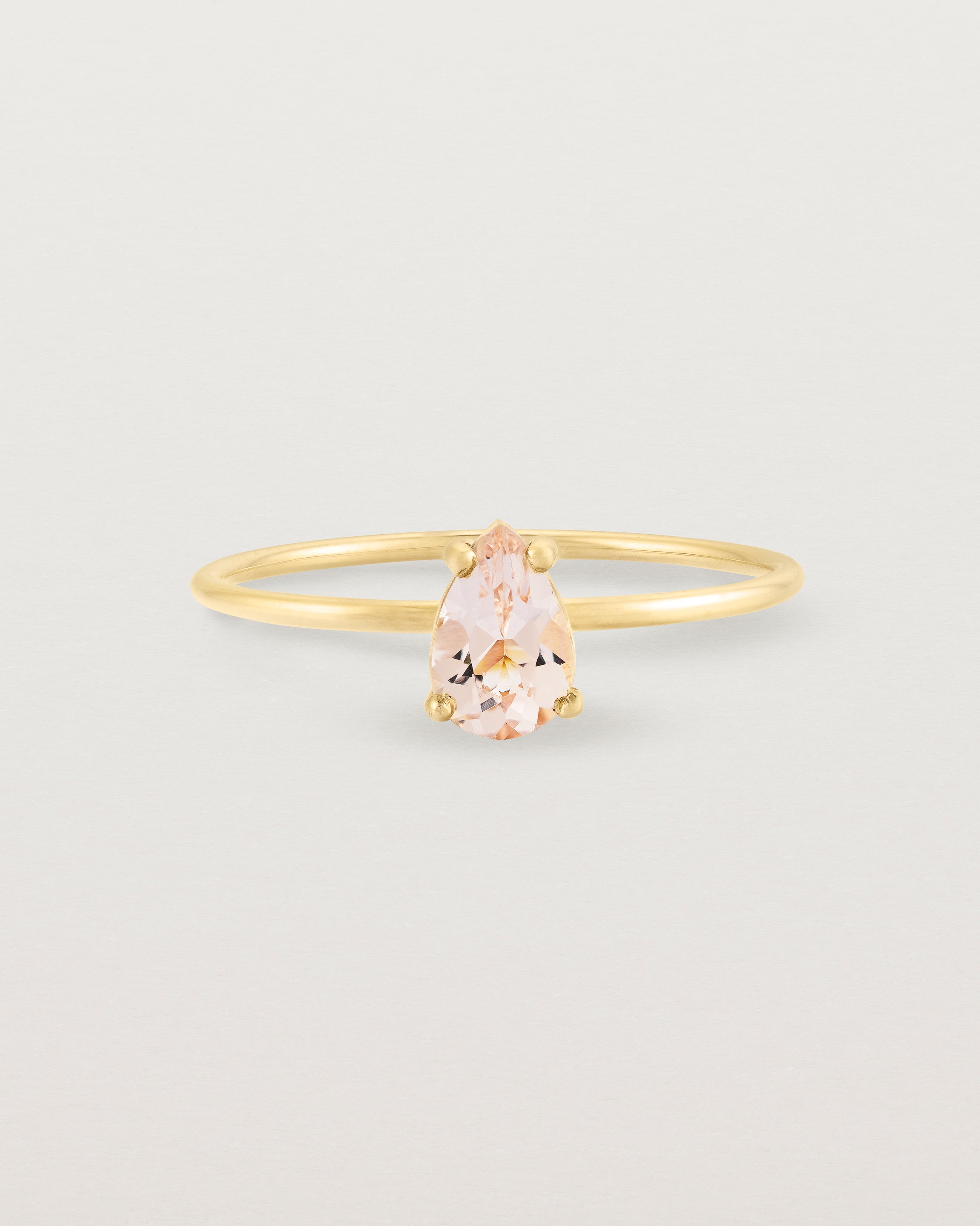 A fine yellow gold ring featuring a pear shaped pink morganite stone