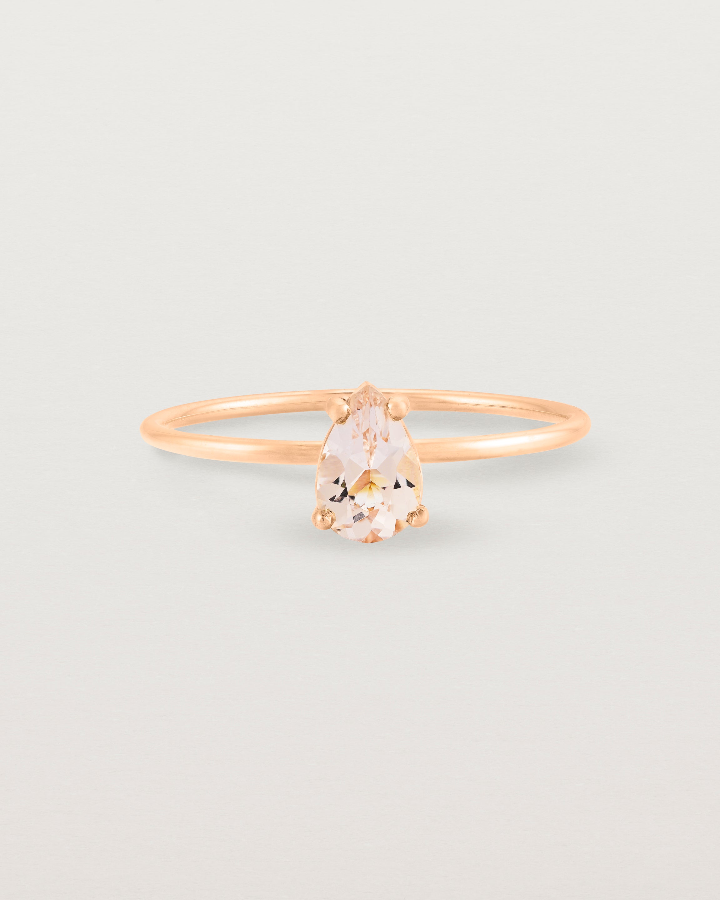 A fine rose gold ring featuring a pear shaped pink morganite stone