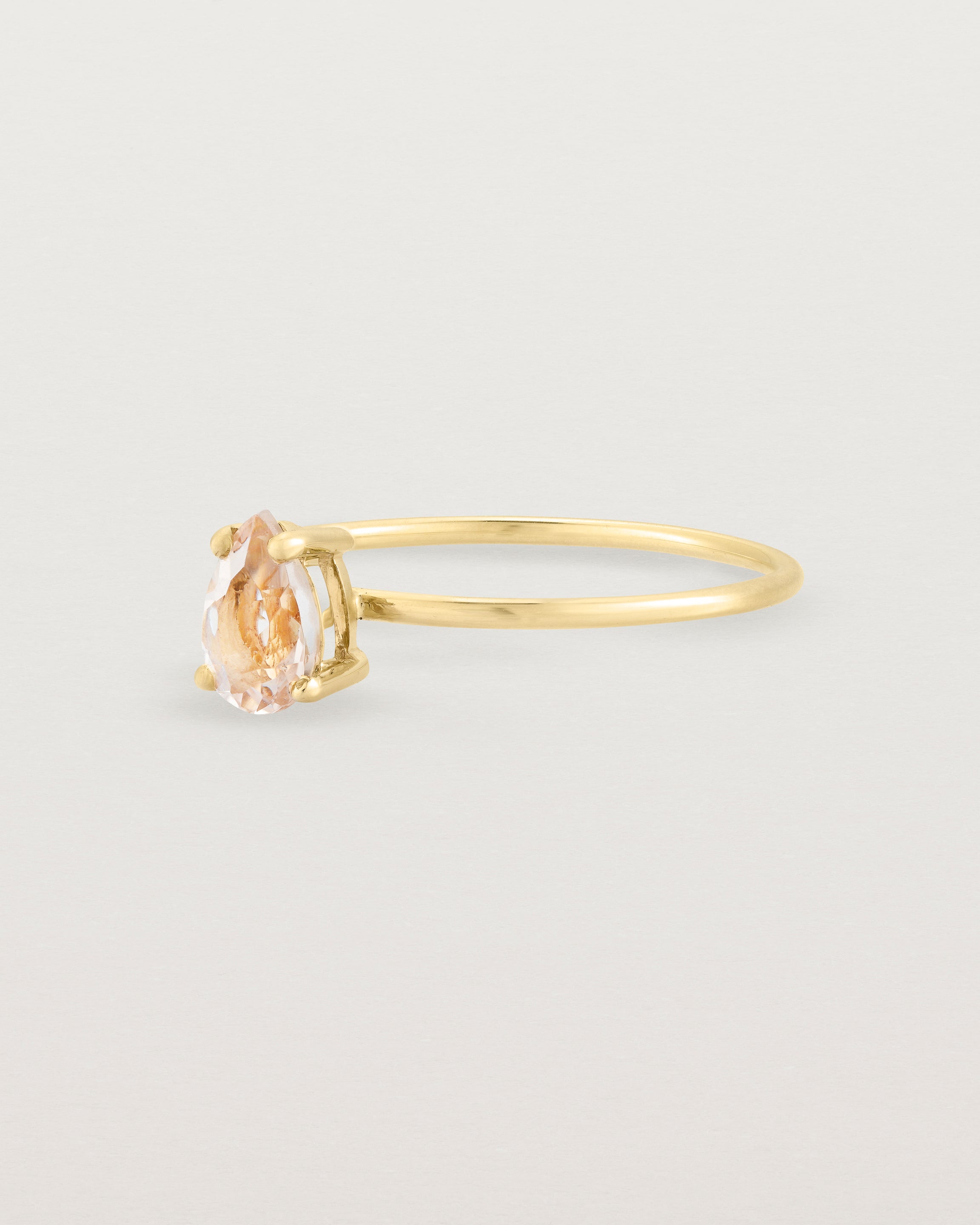 A fine yellow gold ring featuring a pear shaped pink morganite stone