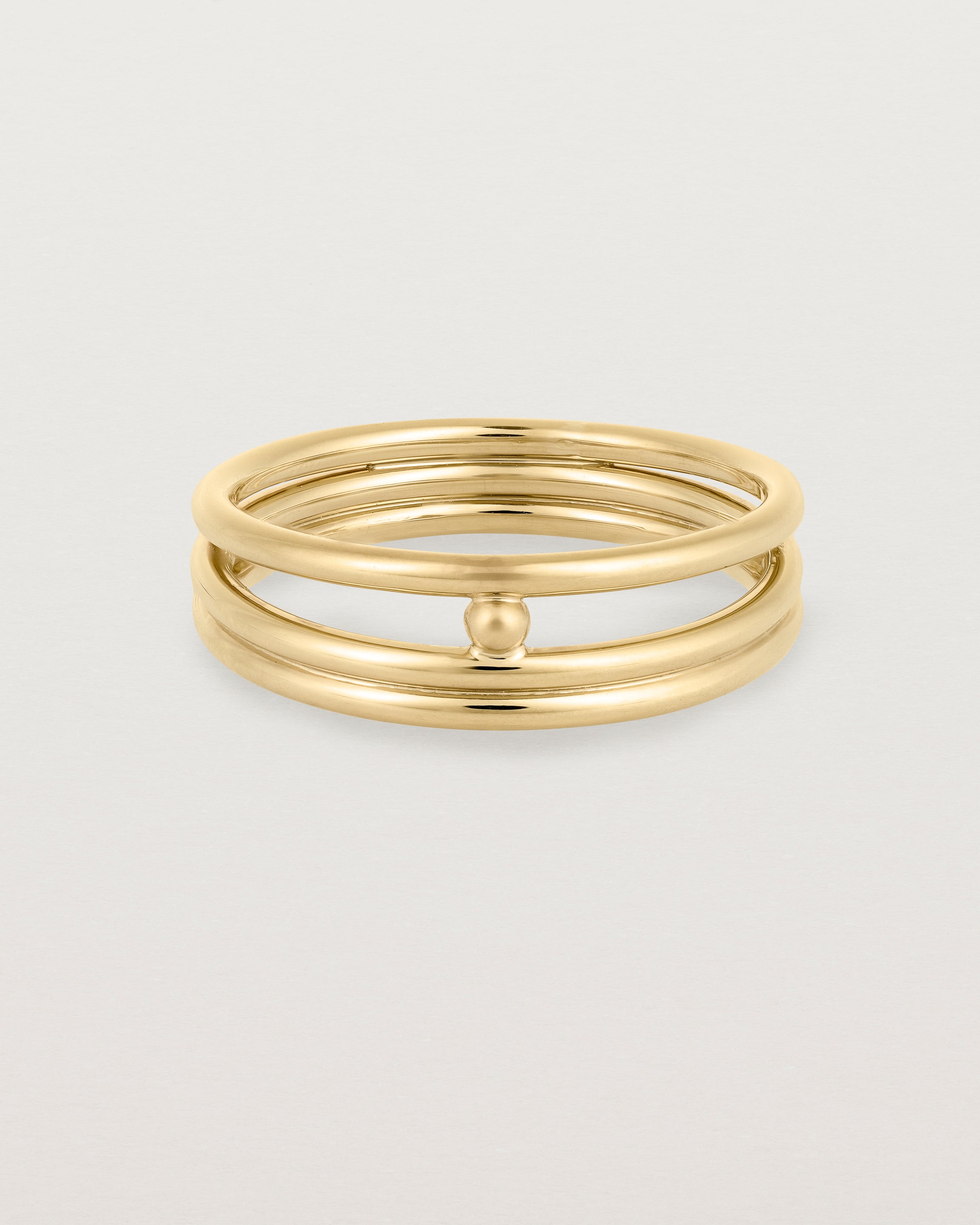 layered yellow gold ring featuring a yellow gold ball suspended between two bands