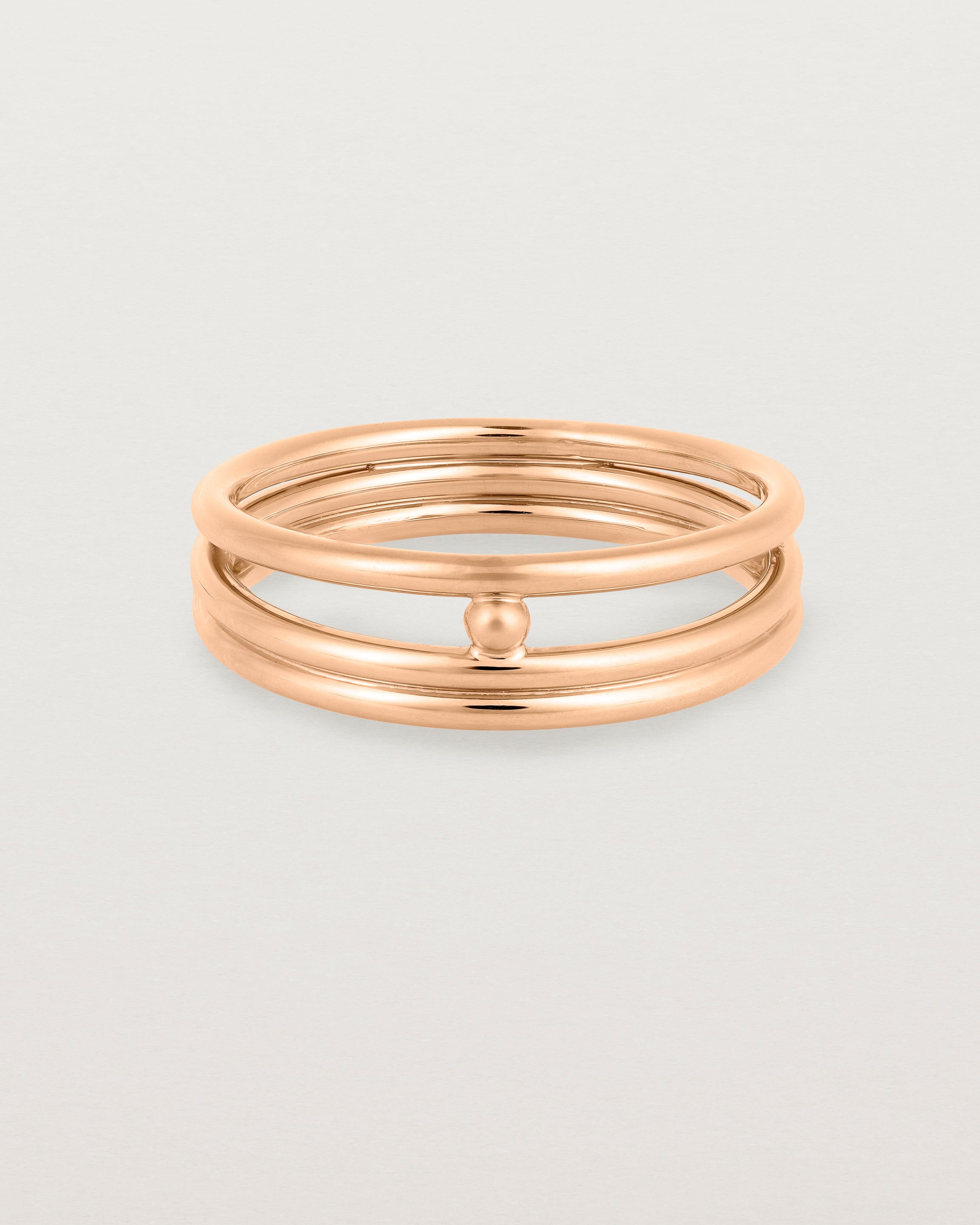 layered rose gold ring featuring a yellow gold ball suspended between two bands