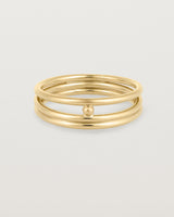 layered yellow gold ring featuring a yellow gold ball suspended between two bands