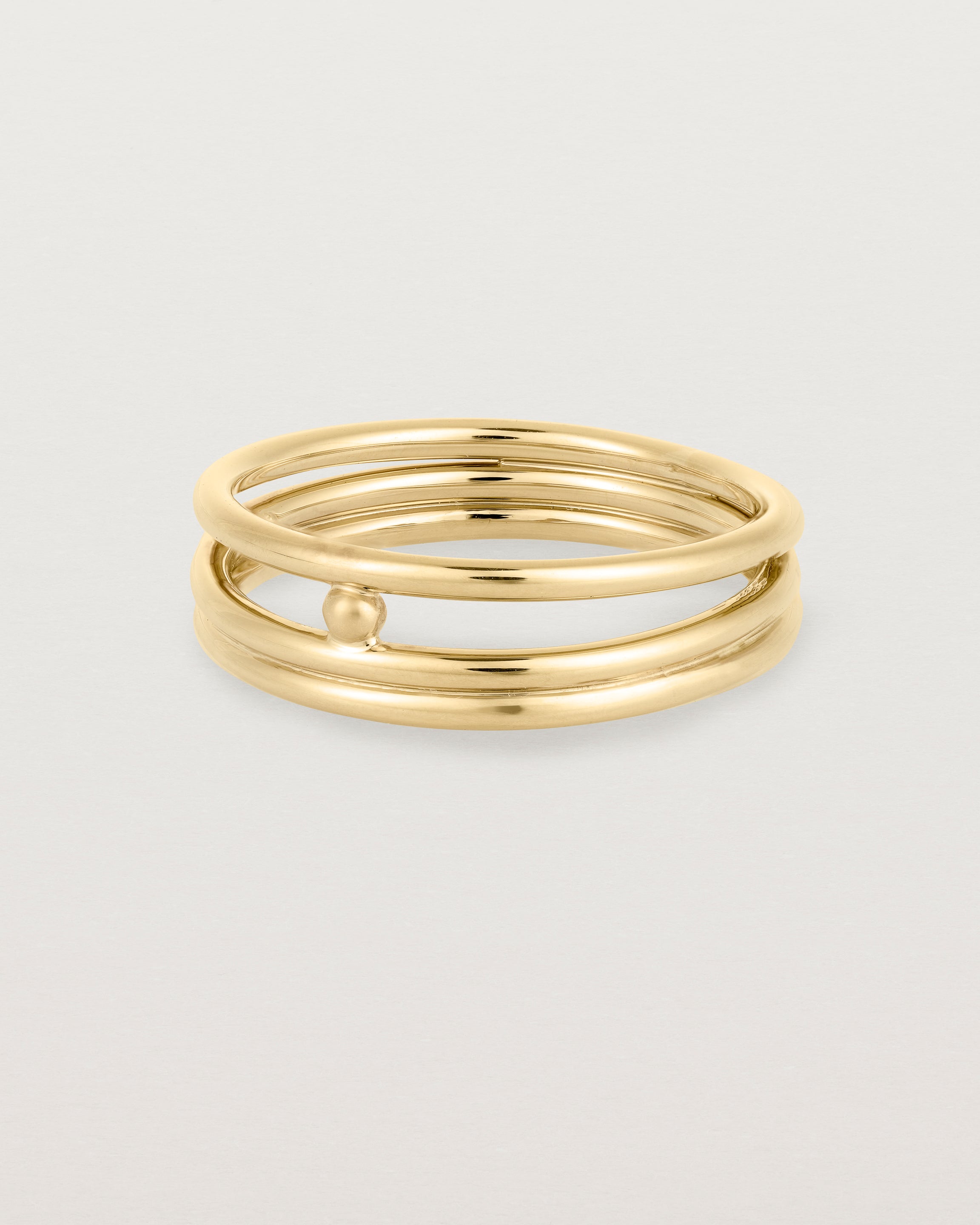 layered yellow gold ring featuring a yellow gold ball suspended between two bands